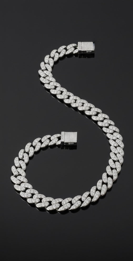 The VLTED 10mm Iced Cuban Link Bracelet, encrusted with sparkling stones, is elegantly arranged in an S-shape on a glossy black surface.