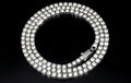 The VLTED 3mm Iced Tennis Chain features three rows of round stones on a silver band, offering street-luxury shine in a dazzling circular design, showcased on a black background.